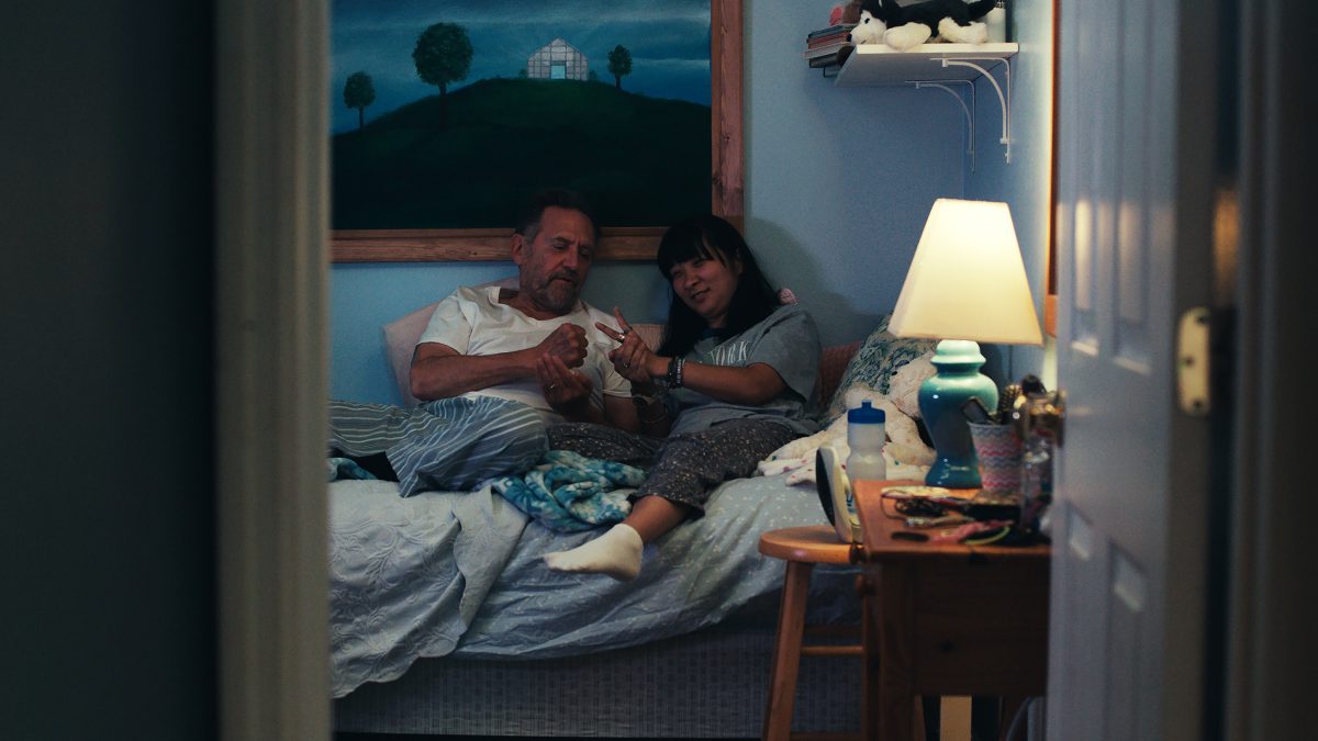 The thing that stays with you the most in Liz Sargent's debut feature, 'Take Me Home,' is the amount of personality she brings to her protagonist, Anna, without letting her be defined by her disability. Anna is brazen, self-assured, and assertive in a way that is rarely seen in cinema. There have, unfortunately, been only a few cases where the story offered disabled persons agency and control over their fate without being reductive. I still remember a film from a few years ago that used the character's condition merely as a plot device to build a cloying melodrama, while focusing on the parents' pain and plight, leaving the character to appear as a crutch — a harmful trope that exploits sympathy by placing helplessness at the narrative core.There have been many cases where ill-informed, ableist notions disregarded the very purpose of telling such stories. Instead of genuinely caring about what they are trying to say with the script, the makers seemed almost entirely preoccupied with presenting themselves in a certain light, simply for telling such a story. None of that remotely applies to Sargent's feature film, or even her eponymous 2023 short, of which her feature offers a bracing narrative extension to. The short film followed Anna, a 30-something Korean-American woman, on a particularly stressful day in her life. Sargent used that premise to address the damning gaps in the American healthcare system, while also telling a gentle tale of sisterhood.  Even when a few narrative beats revealed Anna's sister's frustration in finding Anna a new, comfortable home, that anger was directed at the systemic factors that make this needlessly challenging and tiresome, but never at Anna. The final moments also tied the story in a way that replaced the usual narrative trap of recovery by focusing on the power of emotional embrace. The same applies to Sargent's debut feature, which follows Anna's journey toward reclaiming her agency, where the obstacle is a systemic one, not any flaw in her state of being. In that context, it is also a feminist tale because the character doesn't get what she wants / needs by changing herself, nor does the script present some aspects of her character as something she needs to alter or overcome. The feature film extends the scope of the earlier script by exploring Anna's close-knit relationship with her aging parents, Bob (Victor Slezak) and Joan (Marceline Hugot), living in a suburban neighbourhood in Florida. It features mundane moments in the family's life together to offer a sense of its unhurried pace. We see them caring for one another while living through an extreme heat wave, trying to meet each other's demands or needs, while understanding the root of their frustration or grievances. Despite an occasional friction, it doesn't pit them against each other, nor does it show them holding each other back. We meet a family that is used to each other's behaviors and habits, and trying to find a common ground, just as any other family. That's why the characters feel refreshingly real with distinct personalities. The scenes are written in a way that gives us all these insights organically, without being deliberate or blunt. It's through everyday moments that we learn what independence means for Bob, while being plagued by looming concerns of memory loss. It also offers us a window into Anna's romantic inclinations with grace and respect. Sargent also fleshes out some in-between moments when characters are merely looking at each other or processing something they have realized. It helps us get a more rounded understanding of their prickly but endearing bond. Sargent's actual sister, who stars in the central role of the same name, holds the film on her shoulders. Her assured turn offers every aforementioned insight about her personality. Ali Ahn, who plays Anna's sister, Emily, is an absolute joy to watch on screen. She presents Emily as an effortlessly breezy presence while straddling a path between her professional and familial responsibilities, ensuring everyone's satisfaction. Slezak is remarkable in finding the perfect balance in presenting Bob's outward crankiness with a gentle warmth that shows up in those occasional moments when we see him as his vulnerable self. While Sargeant carefully handles this sensitive subject matter, she deserves just as much praise for her filmmaking approach, which focuses on building a few, relatively long scenes without rushing toward any overarching observation. It gives us a richer understanding of their relationship with a lived-in feel, while gradually redefining our notions about adoption, disabilities, and aging. My only gripe about the film would be the way Sargeant connects the second and third acts. The bridge between those defining moments feels rather underdeveloped. It doesn't communicate anything emotionally memorable, nor does it offer a clear narrative thread as it transitions into the film's final beats. Although you understand the logical reasoning behind what happens before and what comes after, the bridge remains the only underwhelming part of the film. Nevertheless, it doesn't take away much from the sensible beauty that the film gleefully radiates with. Liz Sargent's 'Take Me Home' is a part of the 2026 Sundance Film Festival. Take Me Home (2026) Movie Links: IMDb, Letterboxd Take Me Home (2026) Movie Cast: Anna Sargent, Ali Ahn, Victor Slezak, Marceline Hugot, Shane Harper, April Matthis, Shannon DeVido, Steve Way